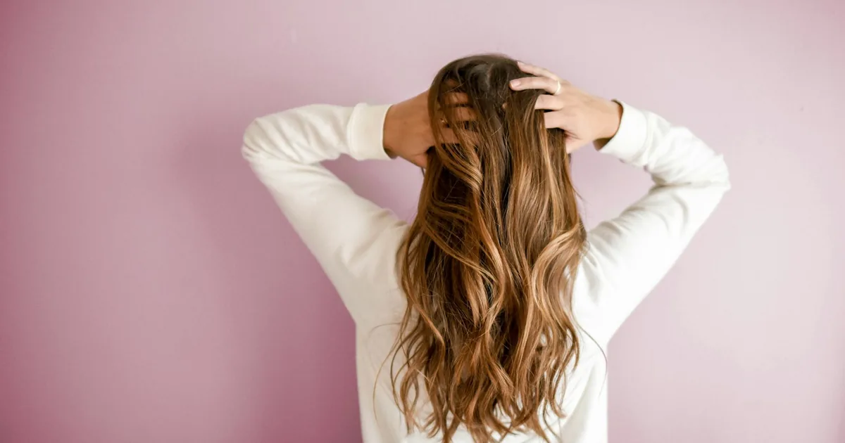Natural brown hair against a pale pink backdrop