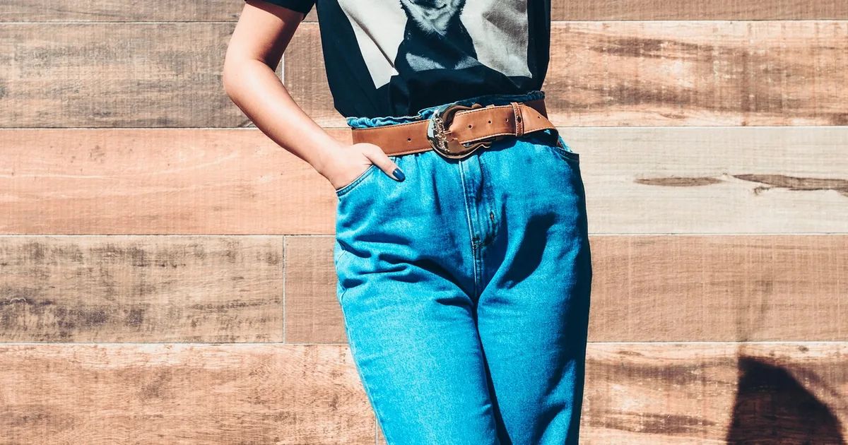High-rise blue jeans with a brown belt on a midsection crop