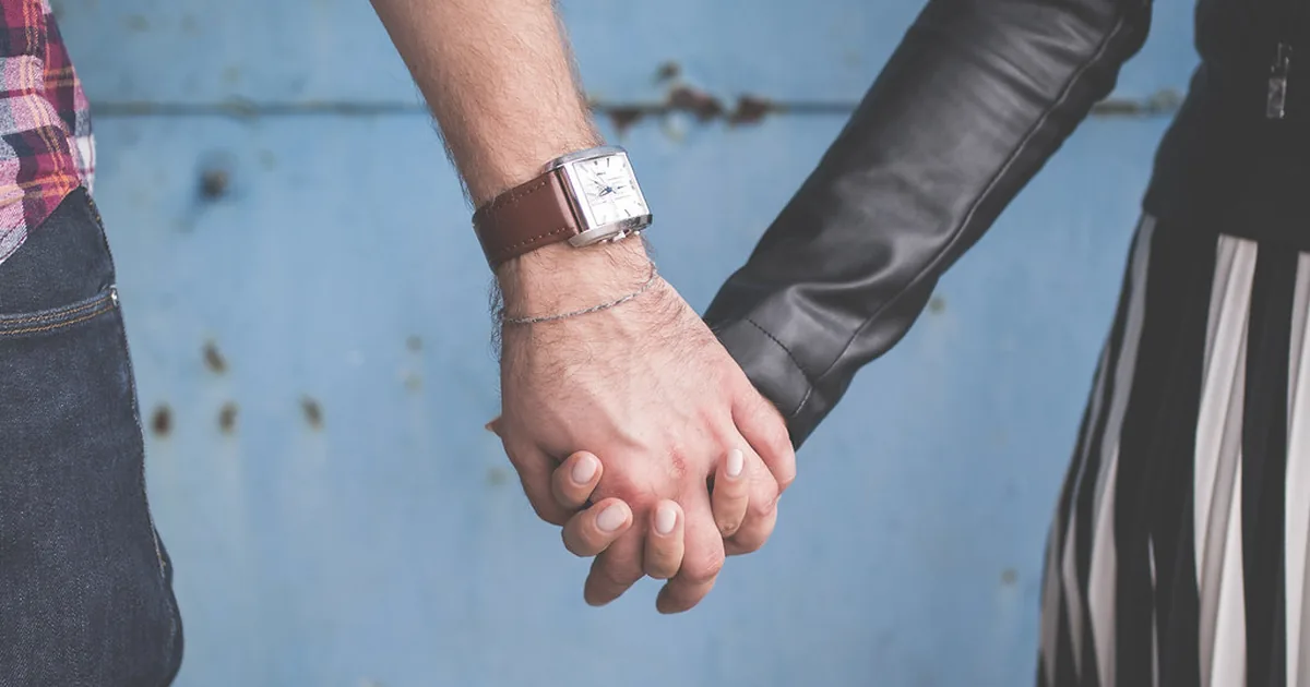 Two people standing together holding hands — the two labelled groups this report compares